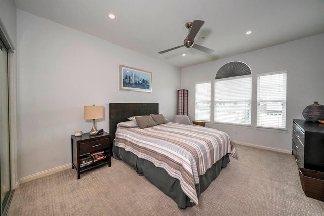 a spacious bedroom with a bed a dresser and a large window