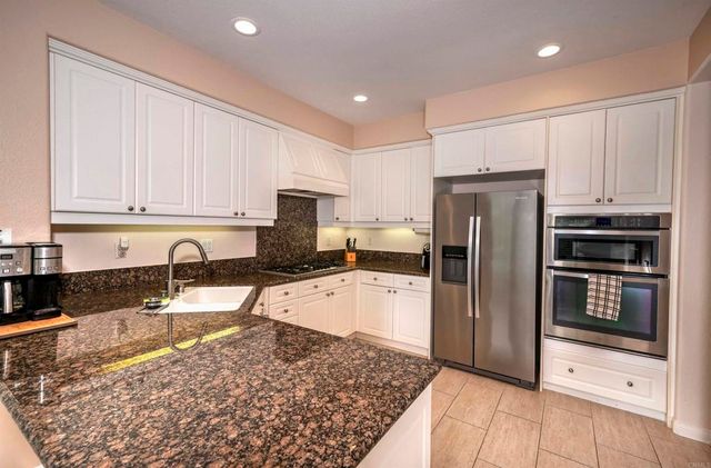 a kitchen with granite countertop a refrigerator and a sink