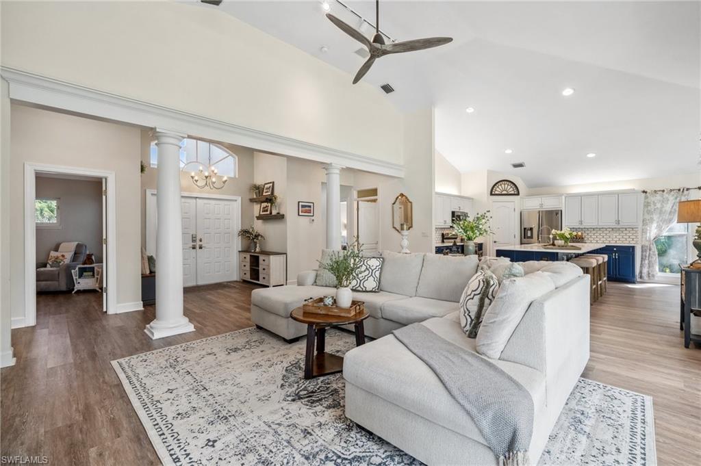 6857 Mill Run Road Naples, FL 34109 - Photo 29 of 49 Living room featuring a ceiling fan, light wood-type flooring, high vaulted ceiling, and ornate columns