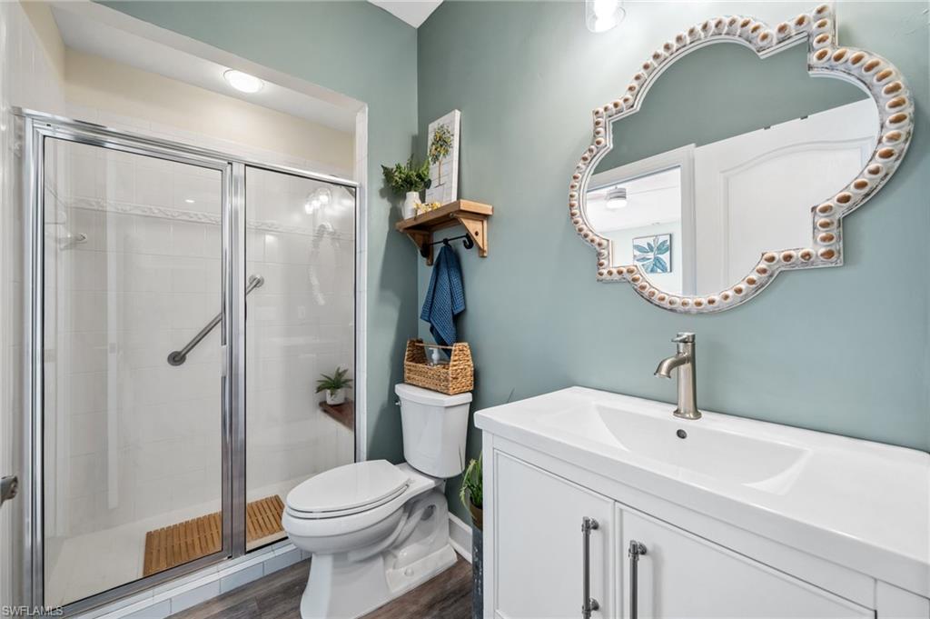 6857 Mill Run Road Naples, FL 34109 - Photo 34 of 49 Bathroom with a stall shower, vanity, toilet, and wood finished floors