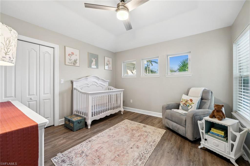 6857 Mill Run Road Naples, FL 34109 - Photo 35 of 49 Bedroom with wood finished floors, a ceiling fan, baseboards, a closet, and a nursery area