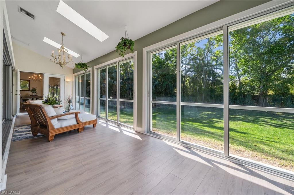 6857 Mill Run Road Naples, FL 34109 - Photo 43 of 49 Unfurnished sunroom with a chandelier, vaulted ceiling with skylight, and visible vents