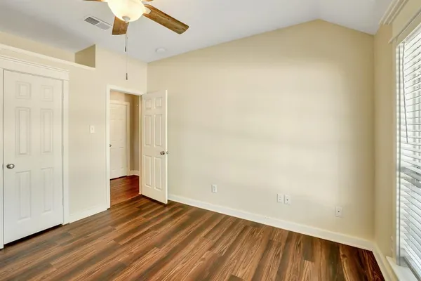 an empty room with wooden floor and windows