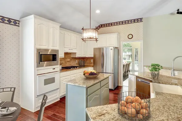 a kitchen with stainless steel appliances granite countertop a refrigerator a oven a sink a stove and white cabinets