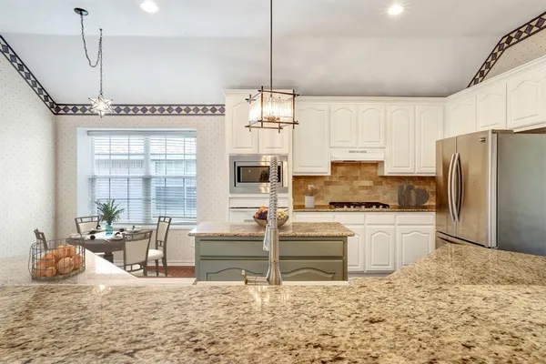 a kitchen with kitchen island granite countertop a stove a sink and a refrigerator