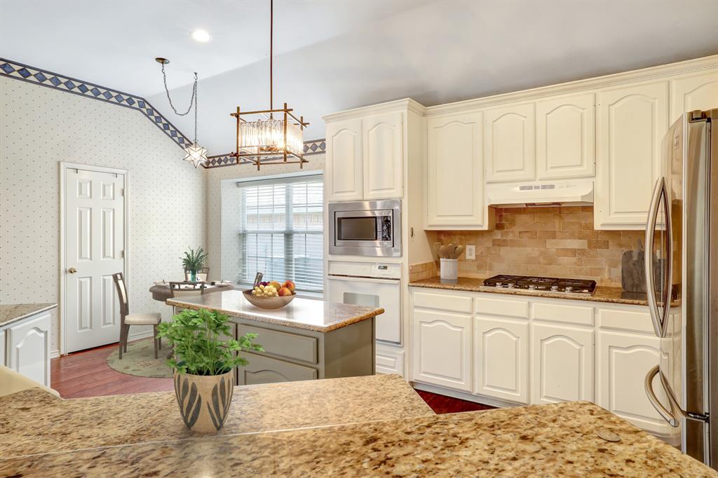 1315 Ballantrae Drive Allen, TX 75013 - Photo 10 of 26 a kitchen with stainless steel appliances granite countertop a stove a sink dishwasher a dining table and chairs with wooden floor