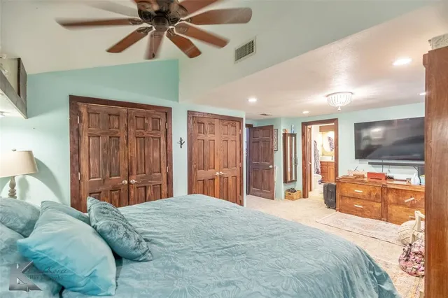 a bedroom with a large bed a flat tv screen and dresser