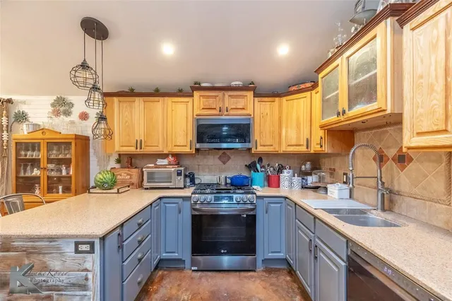a kitchen with stainless steel appliances granite countertop a sink a stove and a wooden floors