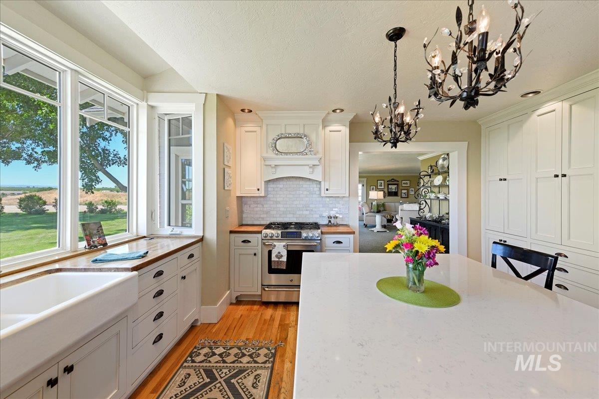 19234 Top Road Caldwell, ID 83607 - Photo 9 of 50 Kitchen with gas stove, decorative light fixtures, white cabinetry, light wood-style flooring, and backsplash