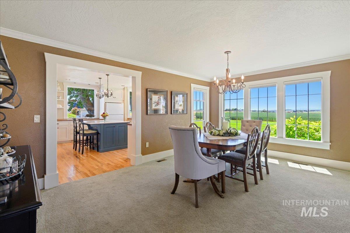 19234 Top Road Caldwell, ID 83607 - Photo 10 of 50 Dining space featuring a chandelier, a textured ceiling, ornamental molding, light colored carpet, and a textured wall