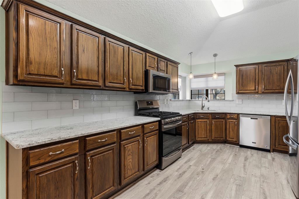 6905 Rochelle Drive Plano, TX 75023 - Photo 8 of 23 a kitchen with granite countertop wooden cabinets stainless steel appliances and a sink