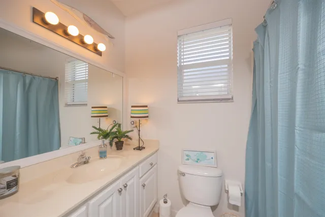 a bathroom with a granite countertop sink toilet and mirror