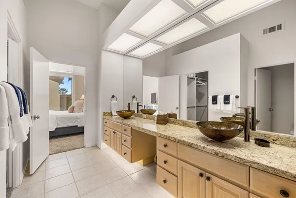 a spacious en suite bathroom with a granite countertop double vanity