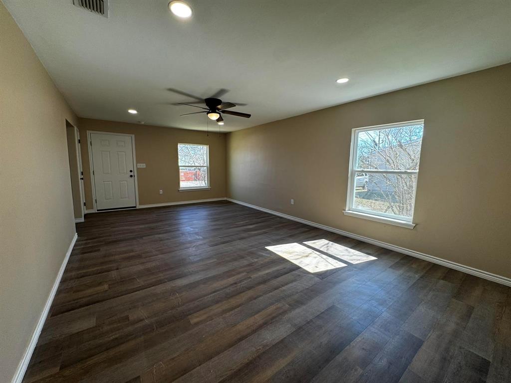 210 Reta Street Stephenville, TX 76401 - Photo 2 of 13 an empty room with wooden floor and windows