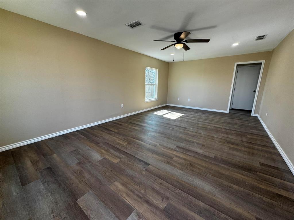 210 Reta Street Stephenville, TX 76401 - Photo 4 of 13 an empty room with wooden floor and windows