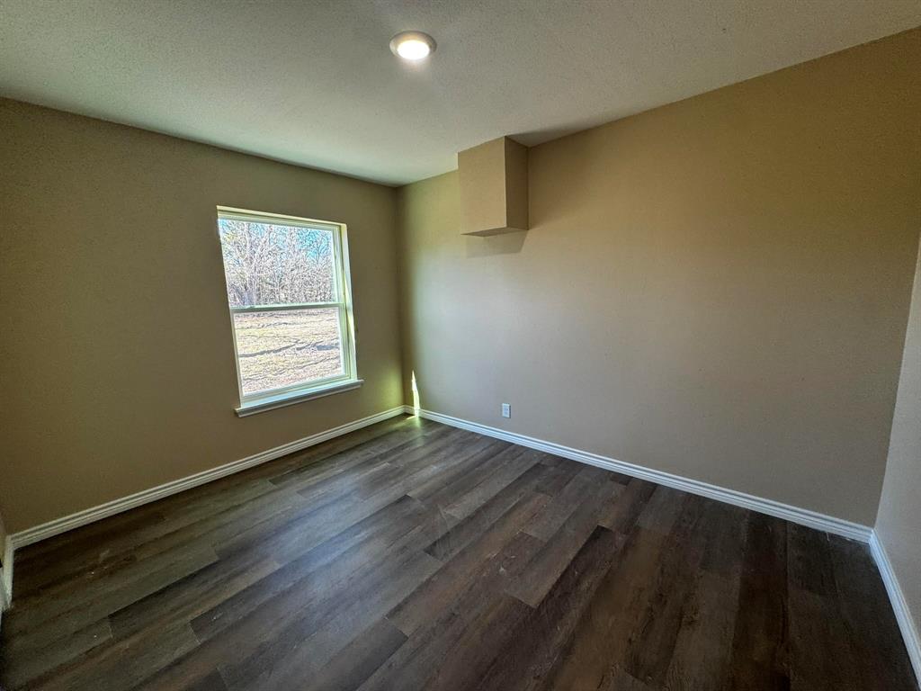 210 Reta Street Stephenville, TX 76401 - Photo 6 of 13 a view of an empty room with wooden floor and a window
