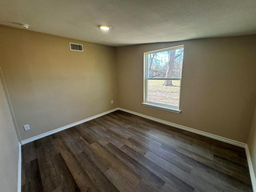 210 Reta Street Stephenville, TX 76401 - Photo 8 of 13 a view of an empty room with wooden floor and a window