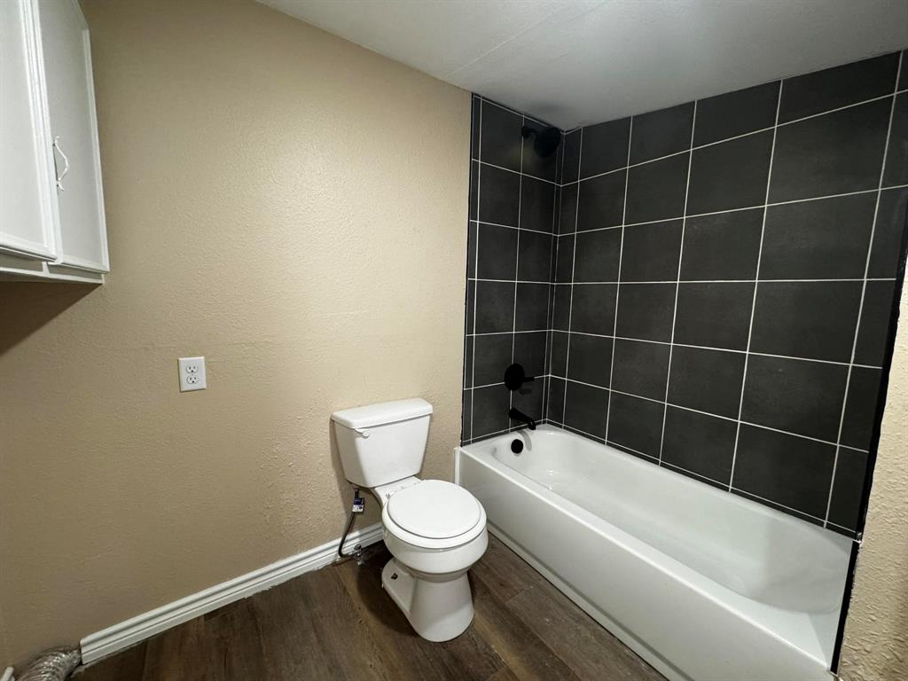 210 Reta Street Stephenville, TX 76401 - Photo 9 of 13 a bathroom with a toilet and a bath tub
