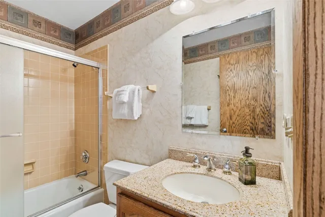 a bathroom with a granite countertop sink a mirror a shower and a bathtub