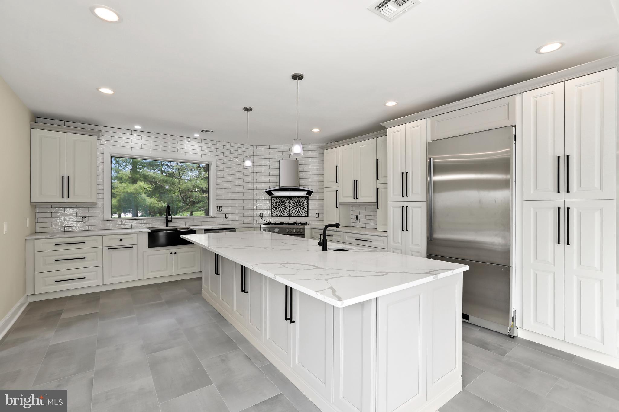 a large kitchen with kitchen island a sink a center island stainless steel appliances and a window
