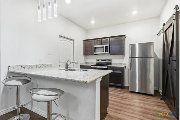 a kitchen with stainless steel appliances granite countertop a sink stove and refrigerator