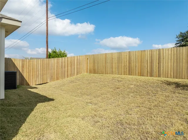 a view of backyard with wooden fence