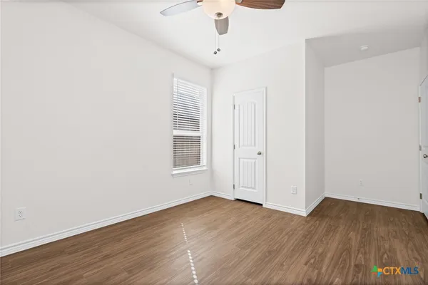 an empty room with wooden floor ceiling fan