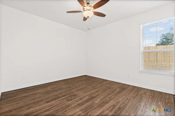 an empty room with wooden floor fan and windows