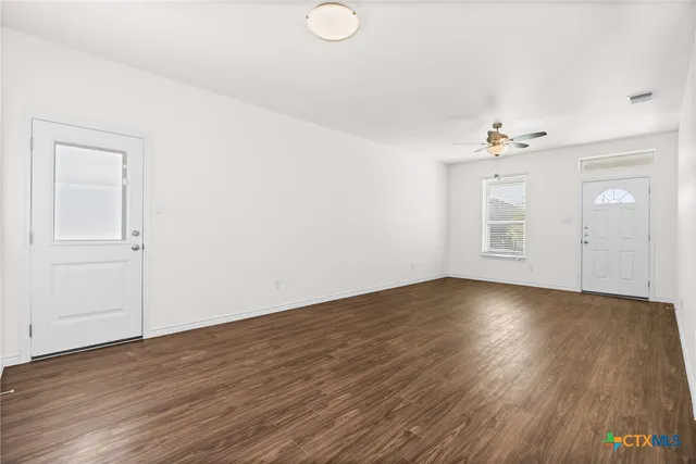 an empty room with wooden floor and windows