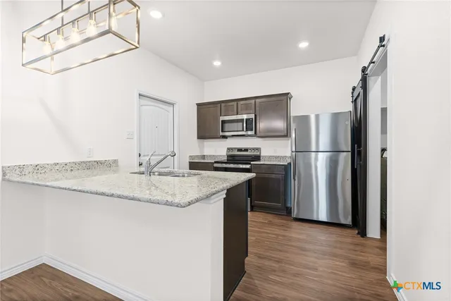 a kitchen with stainless steel appliances granite countertop a refrigerator a sink and a stove