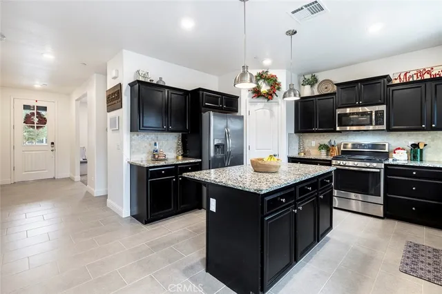 a kitchen with kitchen island granite countertop stainless steel appliances cabinets a sink and a center