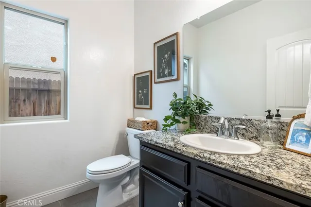 a bathroom with a granite countertop sink a toilet and mirror