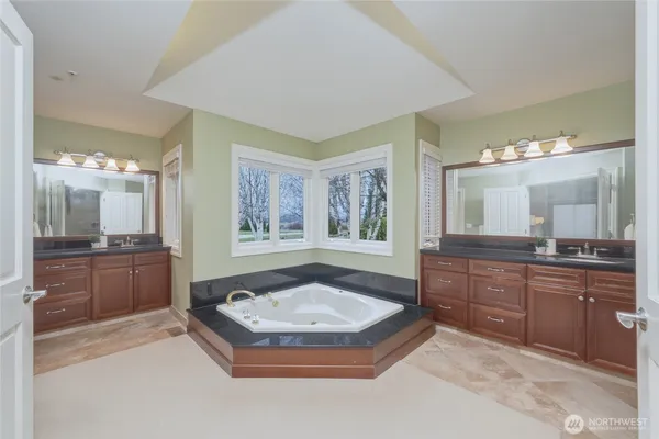 a bathroom with a granite countertop tub sink and mirror