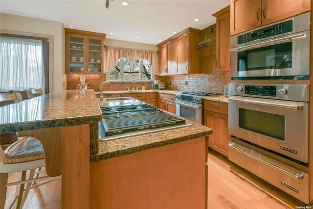 a kitchen with stainless steel appliances granite countertop a stove top oven a sink dishwasher a dining table and chairs with wooden floor