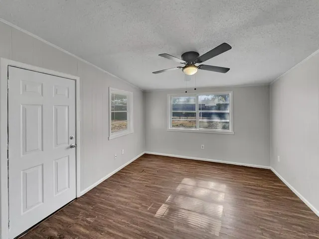 a view of an empty room with a window and wooden floor