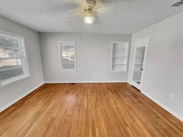 an empty room with wooden floor and windows