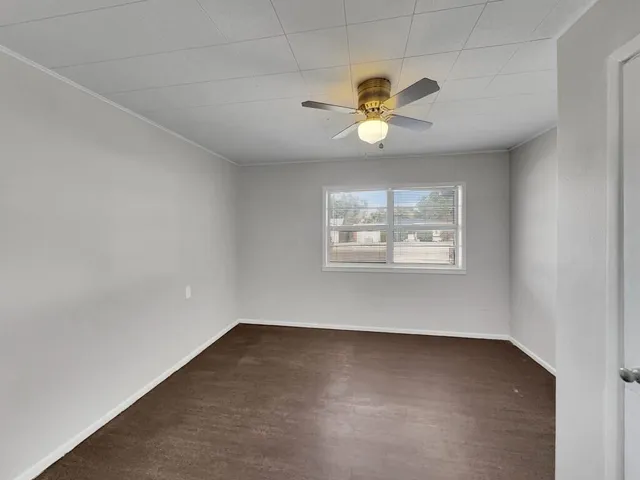an empty room with a window and a ceiling fan