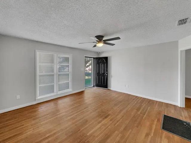a view of an empty room with a window and wooden floor