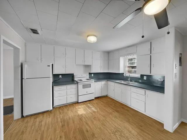 a kitchen with granite countertop a refrigerator and white cabinets