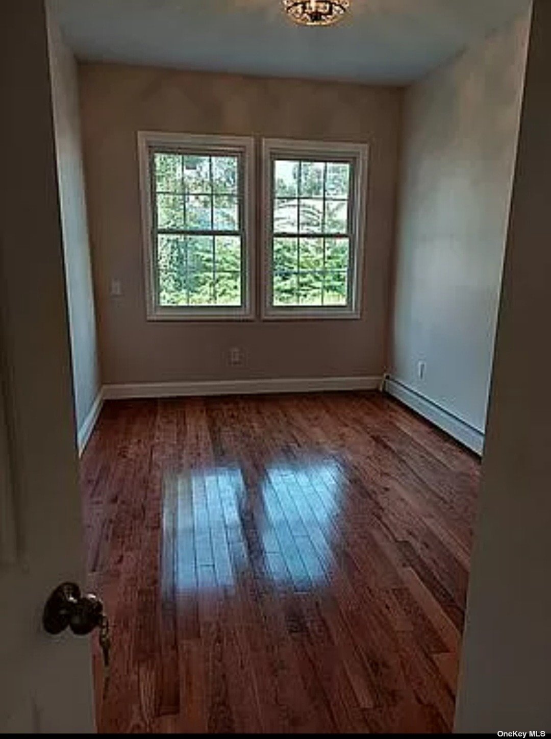 an empty room with wooden floor cabinet and windows