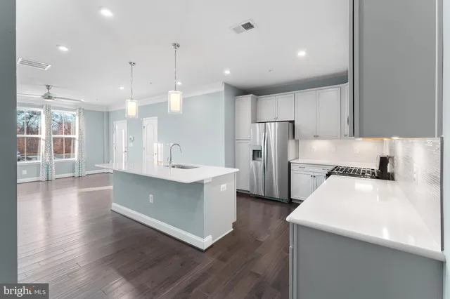 a large kitchen with stainless steel appliances a large counter top a sink a stove and a refrigerator