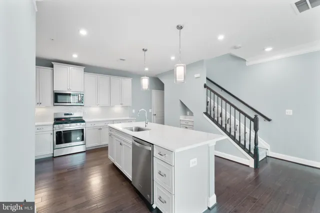 a kitchen with stove a sink and refrigerator with wooden floor