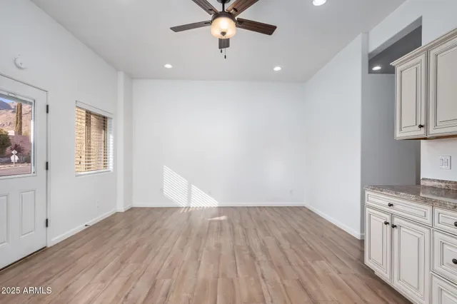 a view of an empty room with a window and wooden floor
