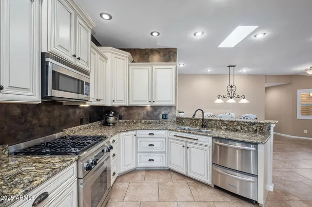 a kitchen with stainless steel appliances kitchen island granite countertop a refrigerator and a stove top oven