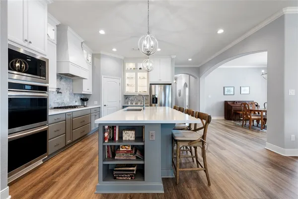 a large kitchen with granite countertop a stove a sink dishwasher a dining table and chairs with wooden floor