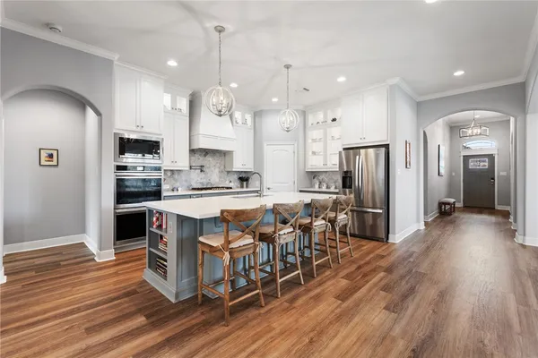 an open kitchen with wooden floor and stainless steel appliances