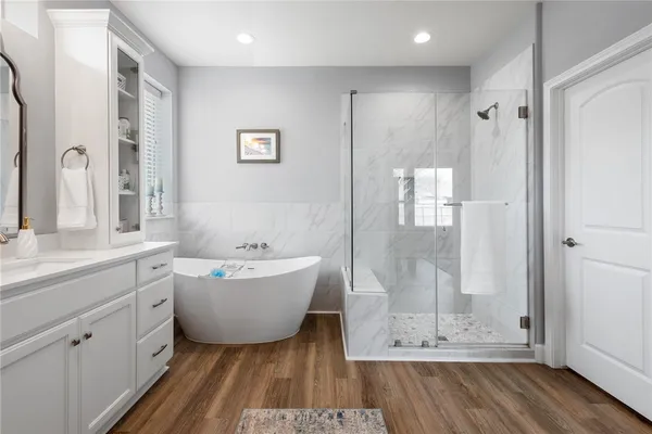 a bathroom with a tub shower sink and mirror