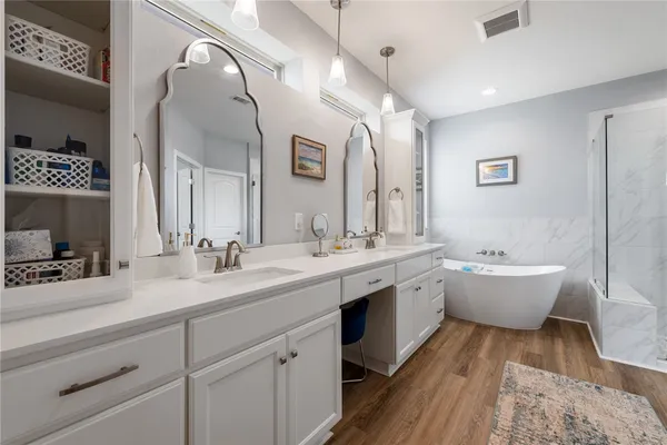a spacious bathroom with a double vanity sink mirror and bathtub