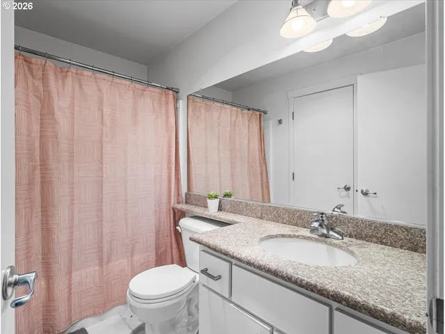 a bathroom with a granite countertop sink a toilet and a mirror