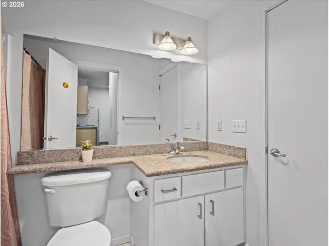 a bathroom with a granite countertop sink a toilet and a mirror
